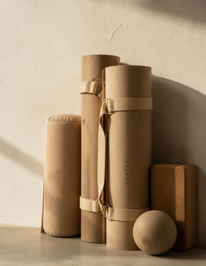 Rolled Pilates mats and props resting against a studio wall